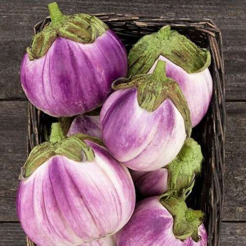 un panier d'aubergine blanches et roses sur une table en bois