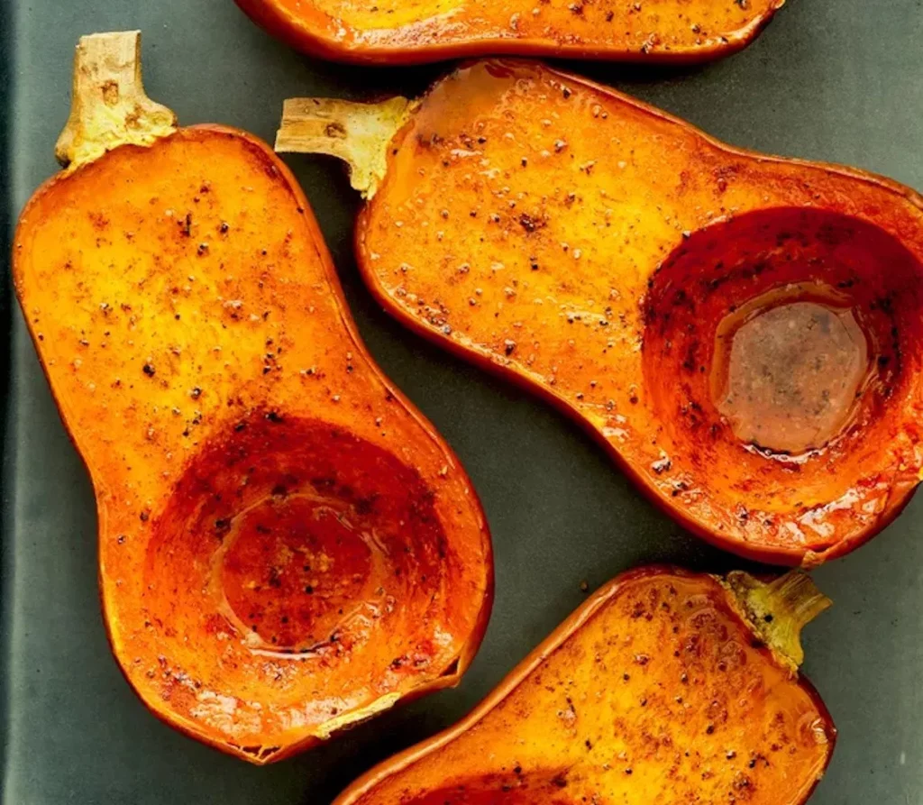 demis courges butternuts passées au four et rotis sur un plat en inox, elles sont vidées