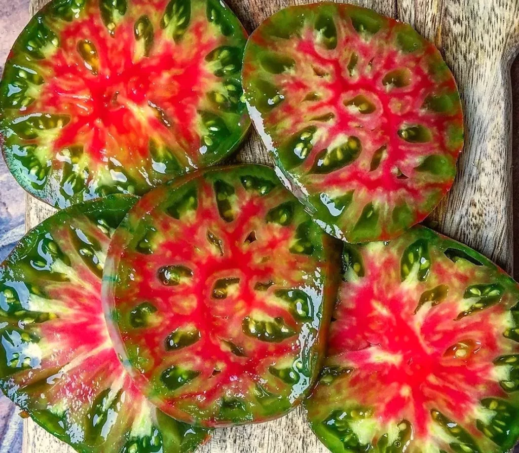 une jolie présentation de tomate ananas noire, elles sont coupées en rondelles sur une planche en bois.