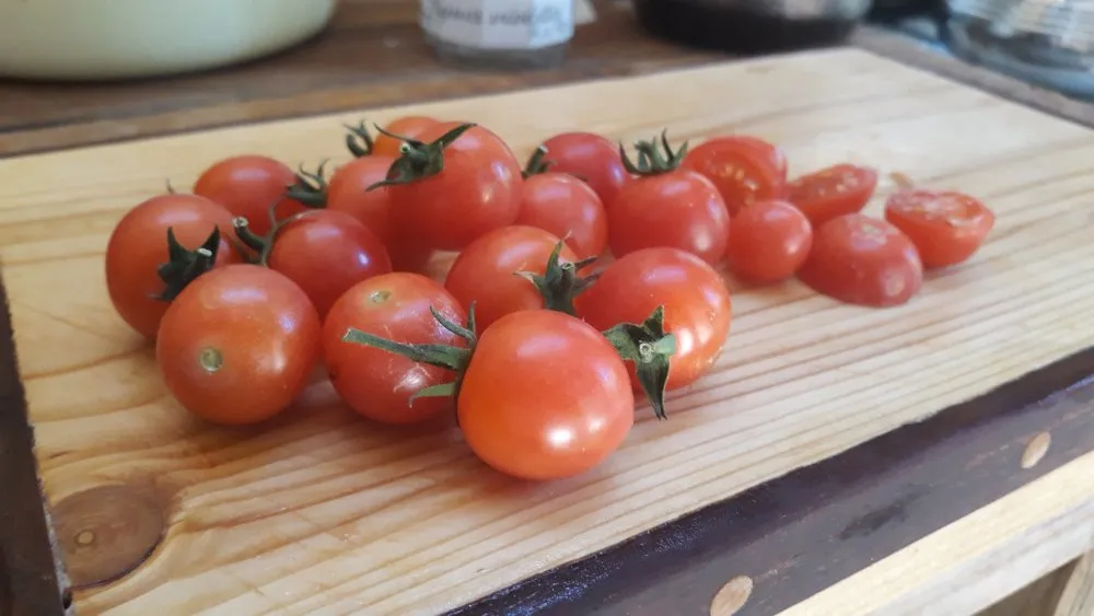 L'image montre des petites tomates rouges sur une planche a découper en bois